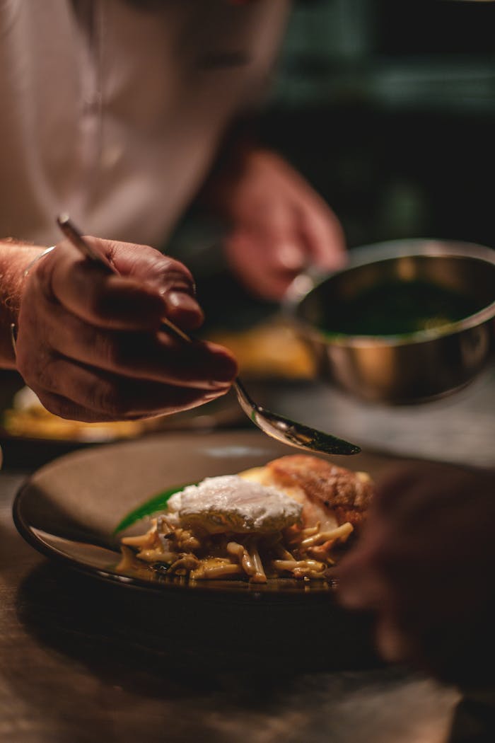 Chef artistically adds sauce to a gourmet dish in a professional kitchen setting.